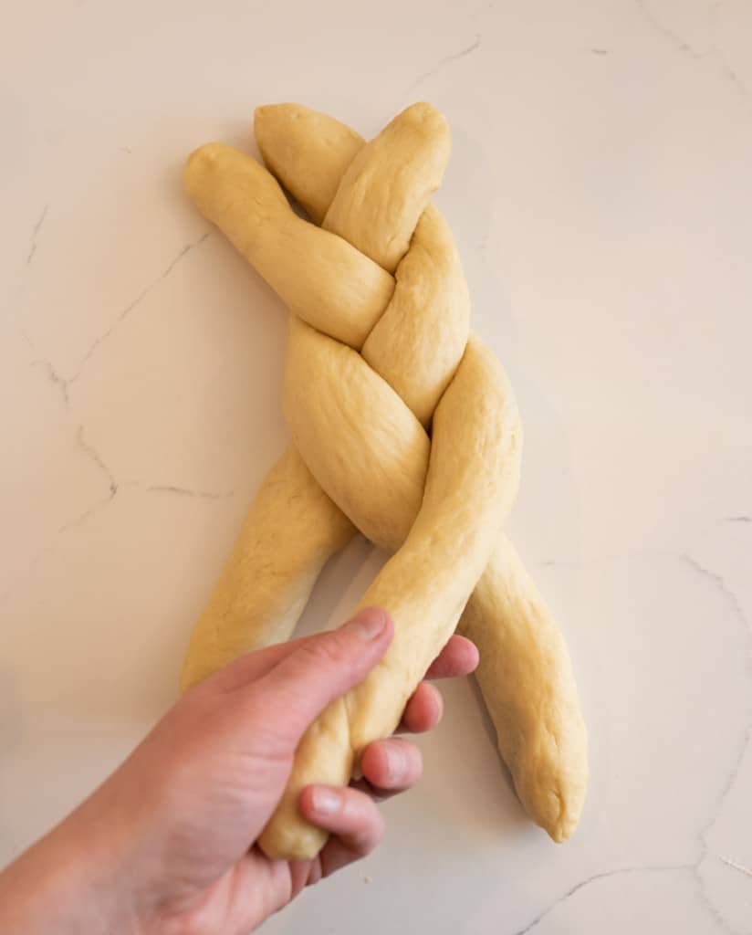 POV with hands platting challah bread dough
