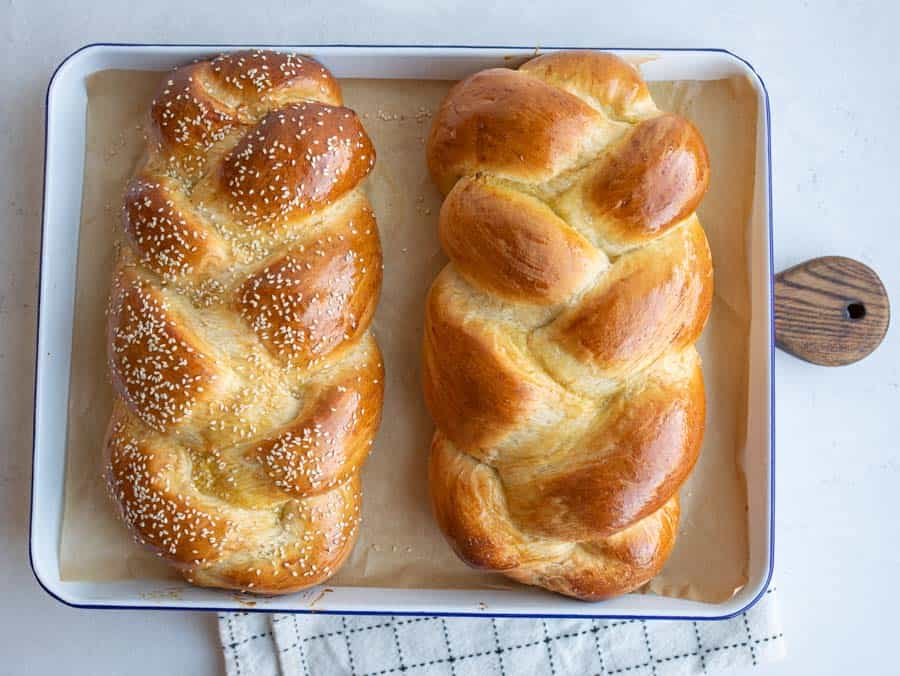two challah bread loafs fresh from the oven, one has sesame seeds