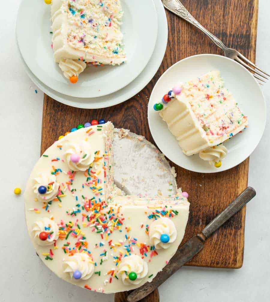 top view whole funfetti sprinkle cake with a slice taken out