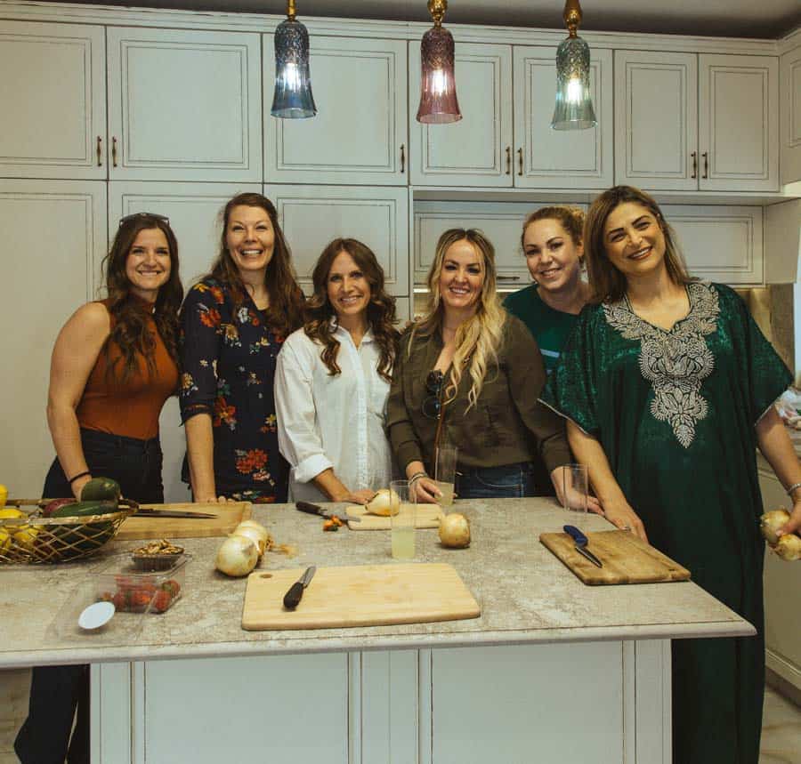 6 women smiling in kitchen during cooking class