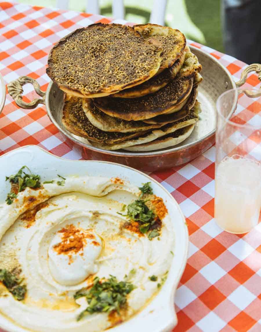 red checkered table cloth with hummus and plate of pita