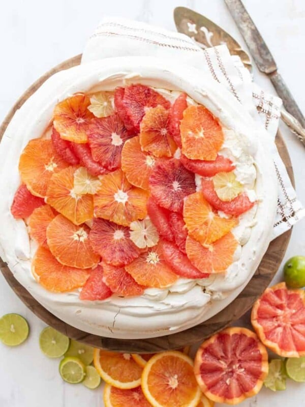 top view of a whole citrus pavlova in a vibrant display of decorative orange, blood orange, and lime cut out to decorate