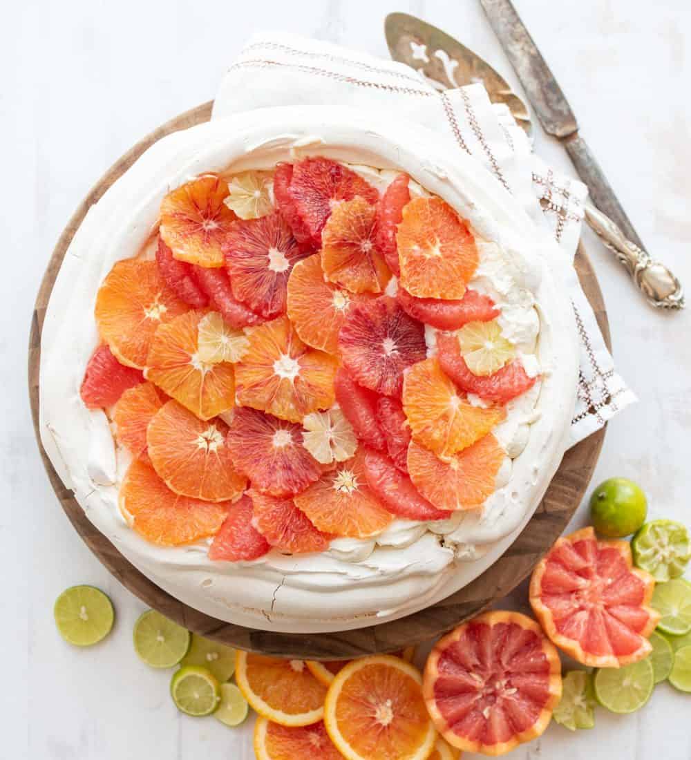 top view of a whole citrus pavlova in a vibrant display of decorative orange, blood orange, and lime cut out to decorate