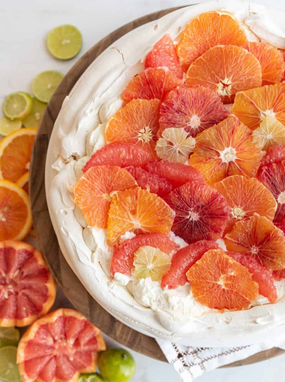 whole citrus pavlova in a vibrant display of decorative orange, blood orange, and lime cut out to decorate