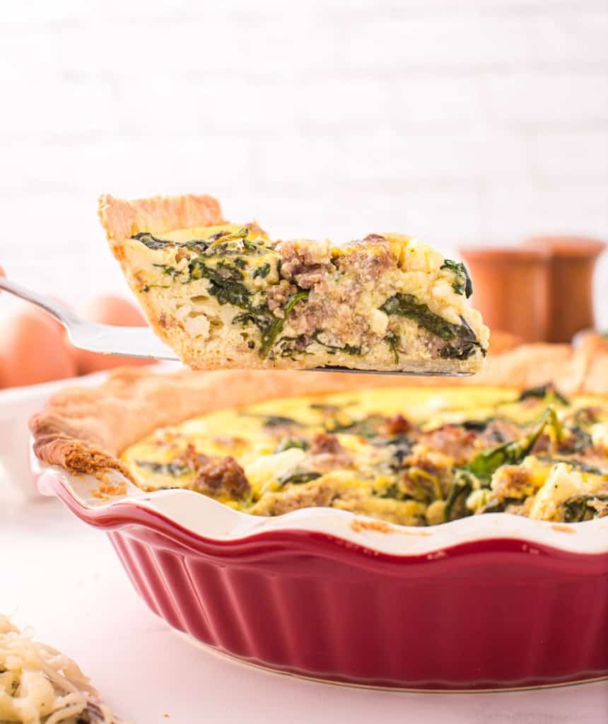 red dish with whole spinach quiche and one slice scooped out