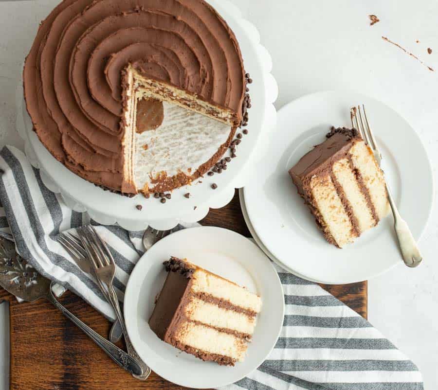 top view of a whole White Cake with chocolate icing with two servings wedged out onto white plates