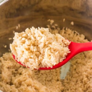 brown rice in a pressure cooker on a red spoon