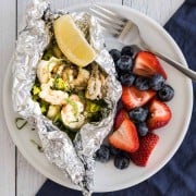 grilled shrimp foil packet dinner on a plate with berries on the side