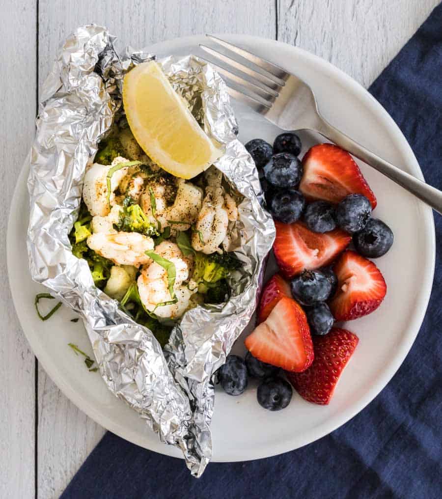 grilled shrimp foil packet dinner on a plate with berries on the side