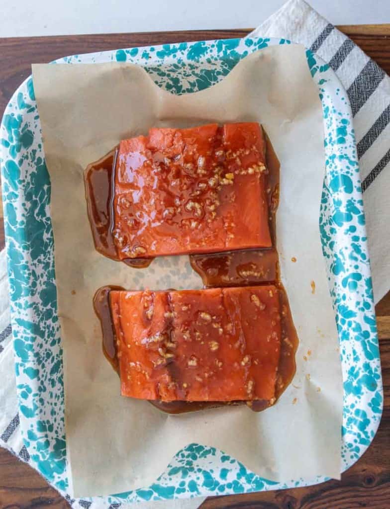 honey glazed and seasoned salmon in a baking dish on parchment