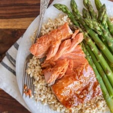 honey glazed salmon dinner on a plate over rice with asparagus as a side