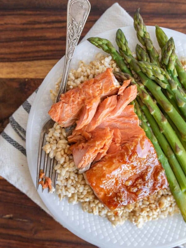 honey glazed salmon dinner on a plate over rice with asparagus as a side