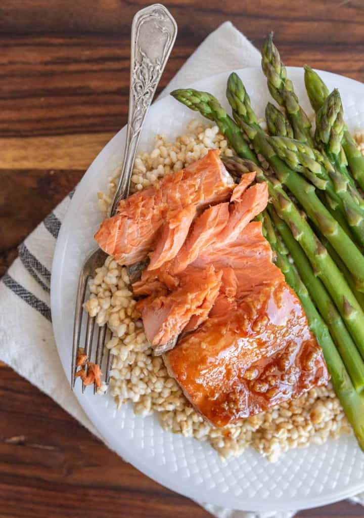 honey glazed salmon dinner on a plate over rice with asparagus as a side