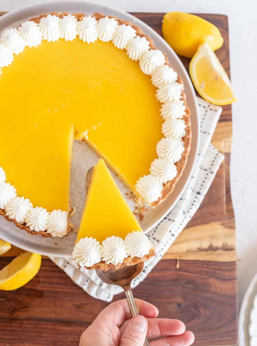 top view of lemon tart with a slice being removed POV