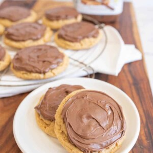 two peanut butter nutella cookies on a plate with the rest on a cooling rack behind