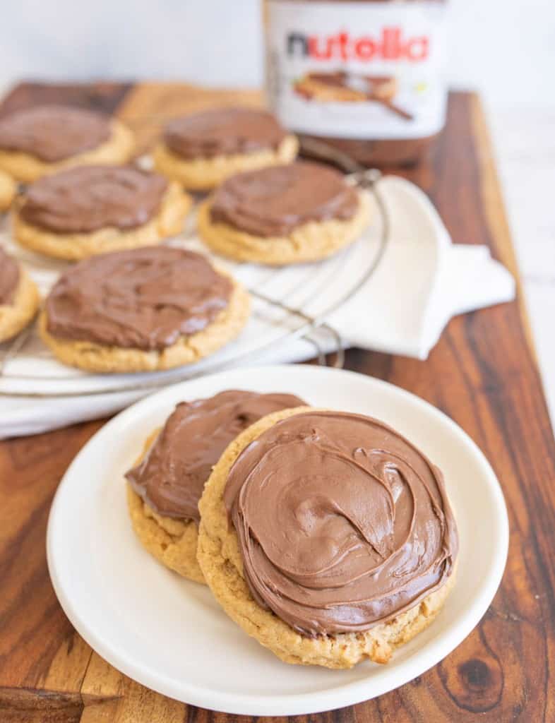 two peanut butter nutella cookies on a plate with the rest on a cooling rack behind