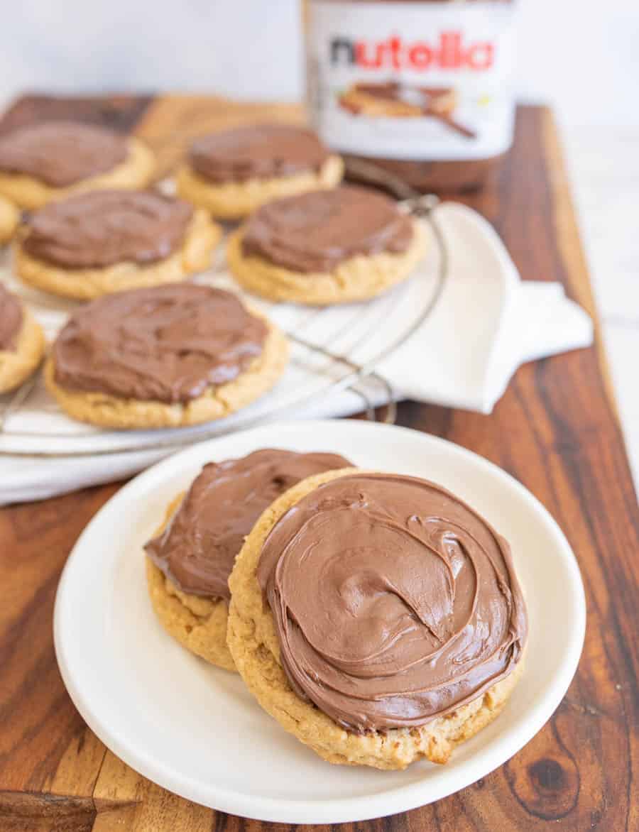 two peanut butter nutella cookies on a plate with the rest on a cooling rack behind