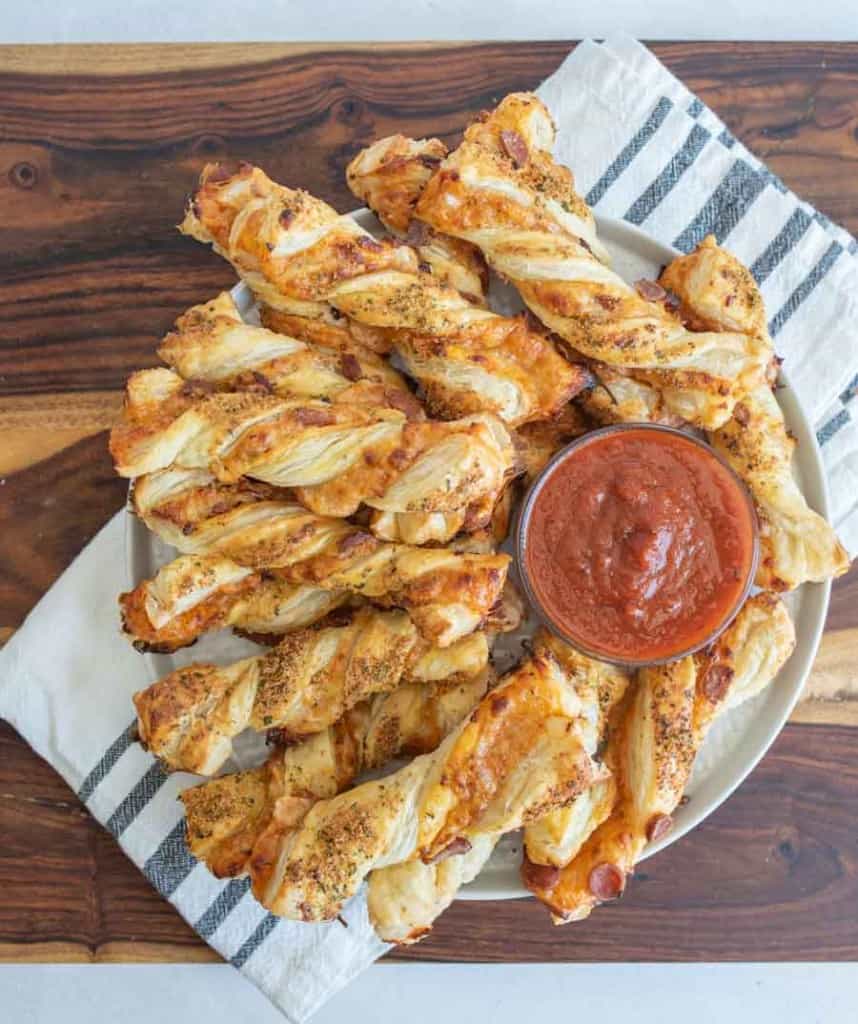 top view of a plate of pizza twists with marina dipping sauce in the middle