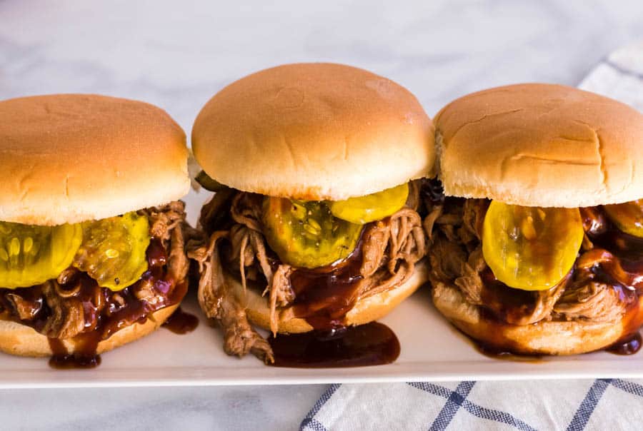 three barbecue pulled pork sandwiches on a plate