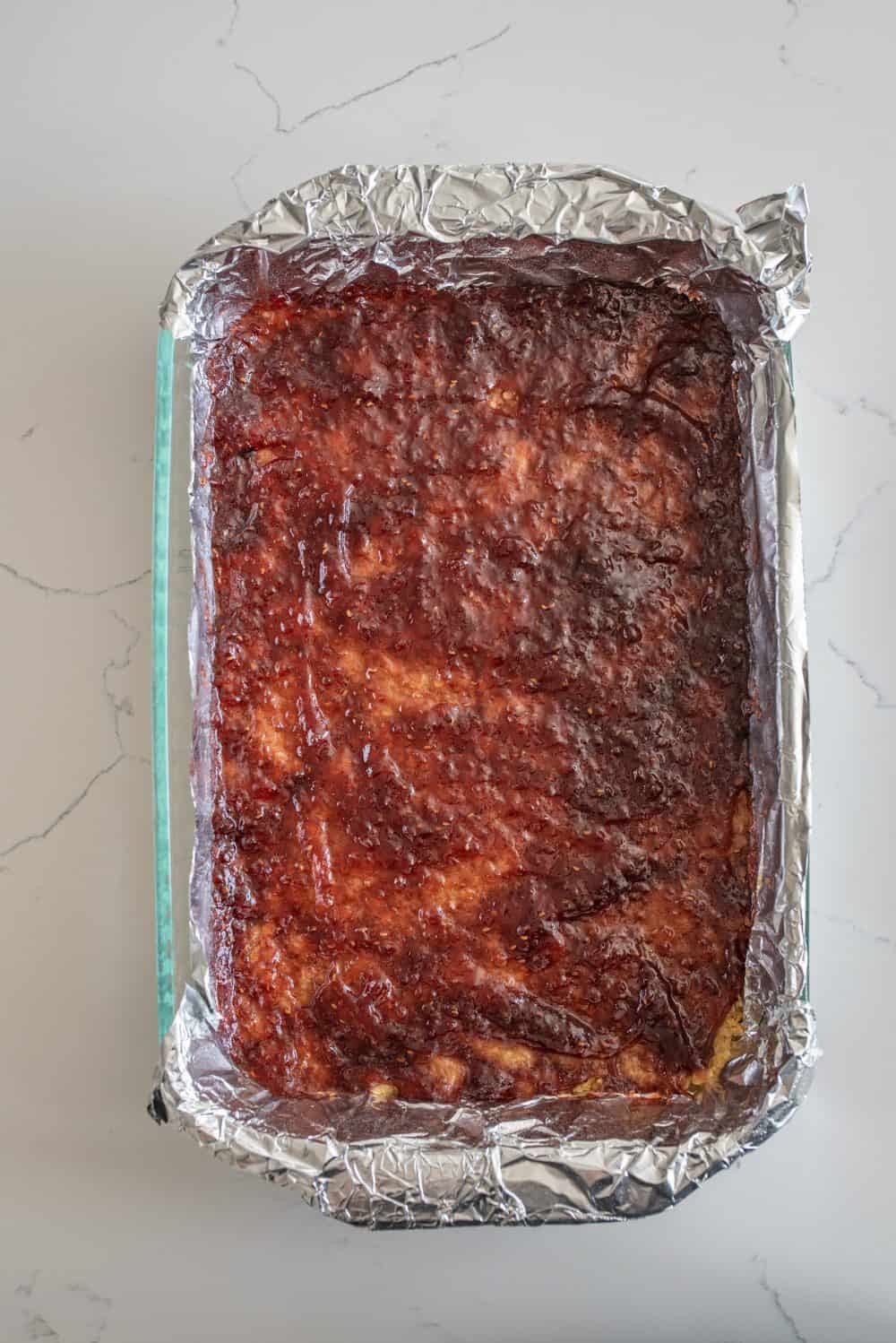 top view of the pan of raspberry cheesecake bars with the raspberry sauce