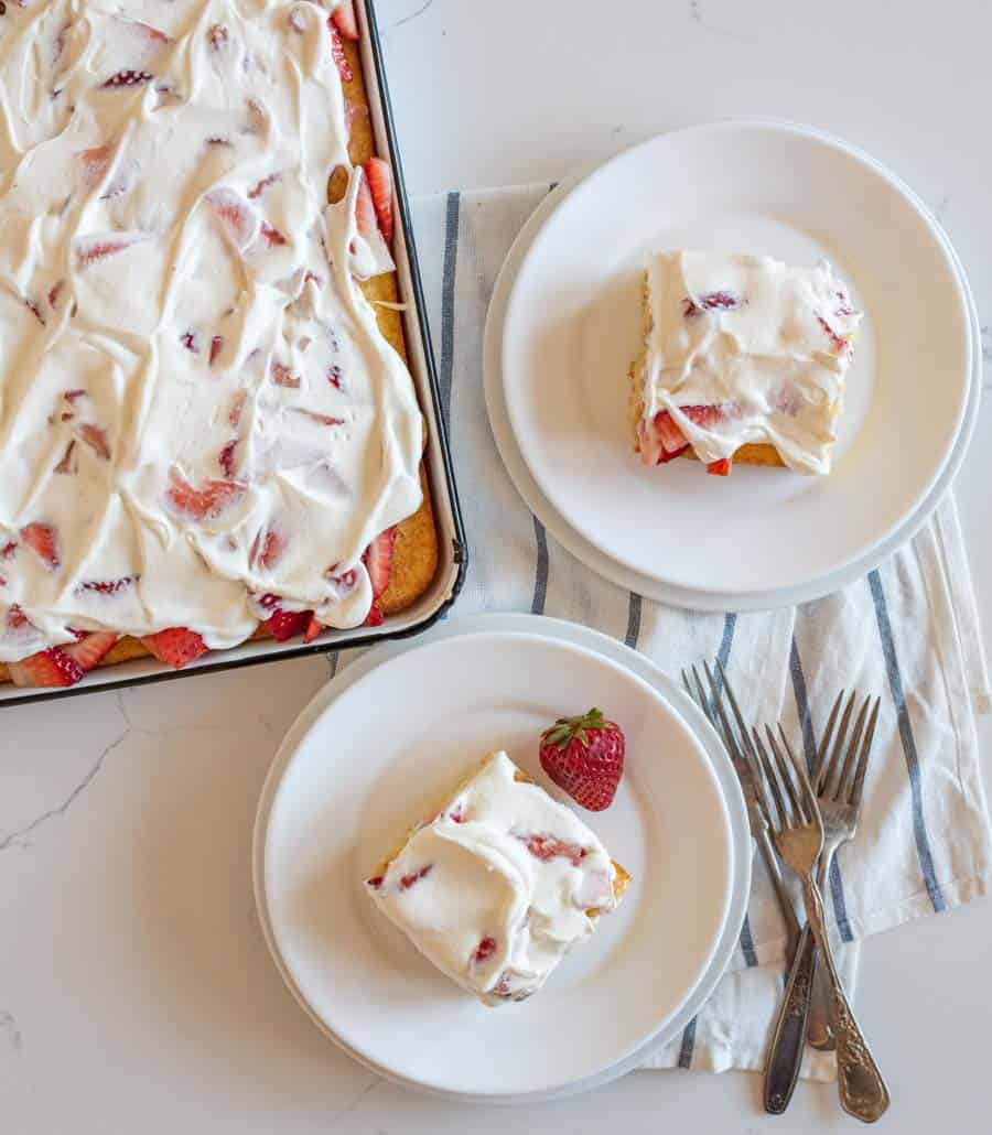 top view of a sheet pan strawberry shortcake and two servings dished onto white plates