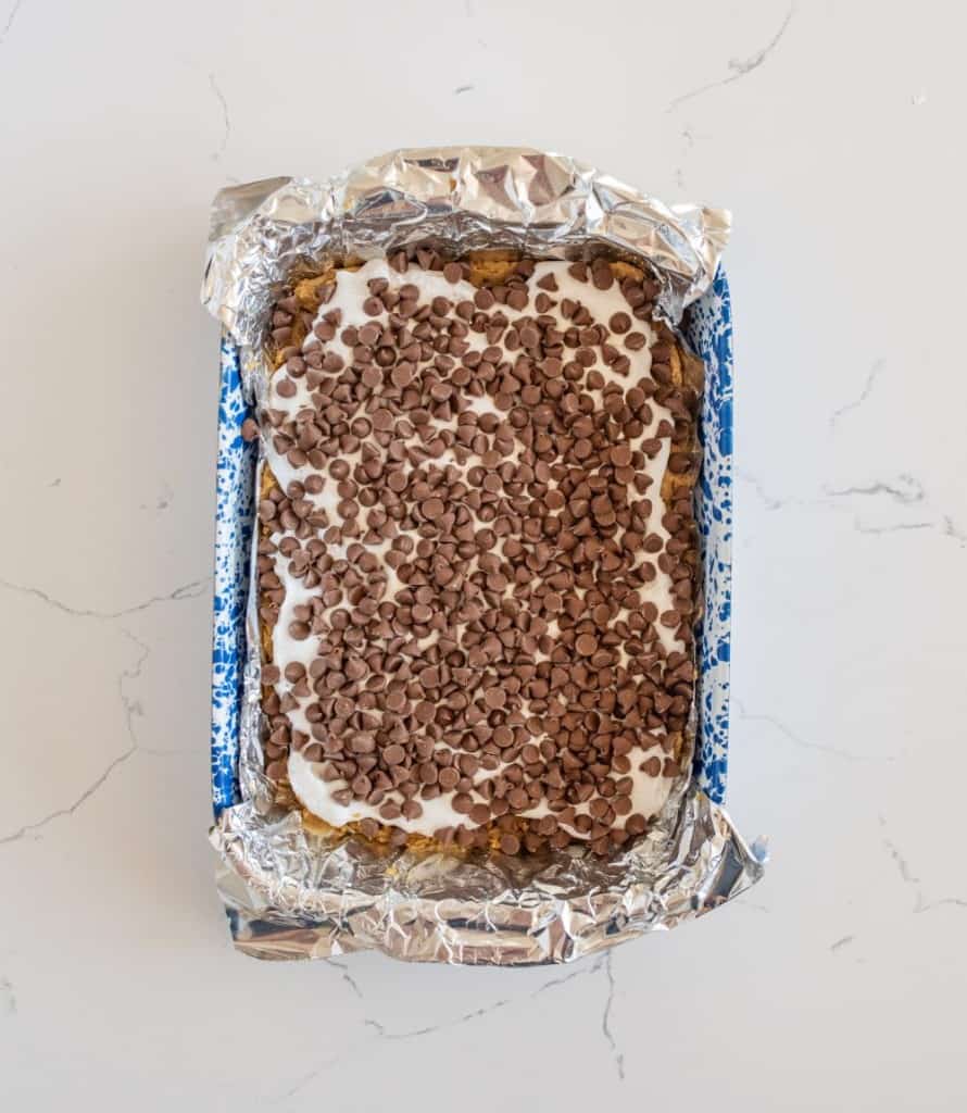layering process of smores cookie bar shown in a pan