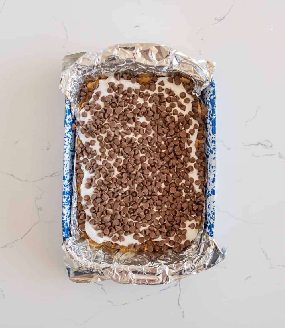 layering process of smores cookie bar shown in a pan