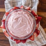 a bowl filled with strawberry buttercream decorated with fresh sliced berries all around