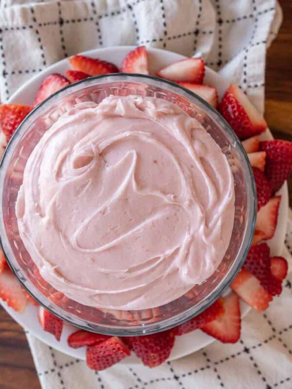 a bowl filled with strawberry buttercream decorated with fresh sliced berries all around