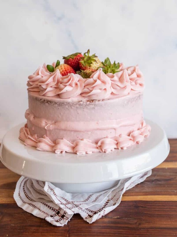 whole pink strawberry cake with strawberry buttercream and whole strawberries on top