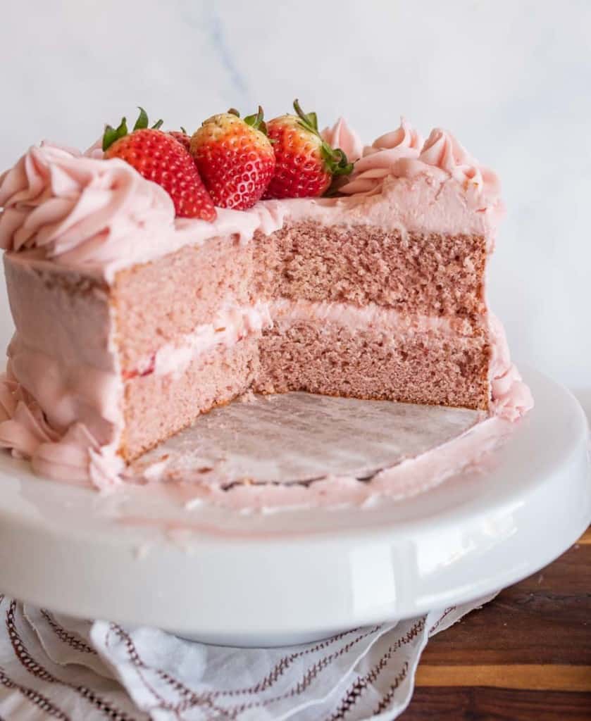 whole pink strawberry cake with slices removed