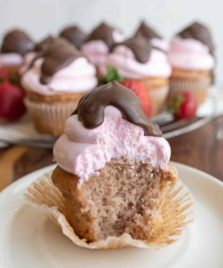 strawberry cupcakes with chocolate on top with a bite out