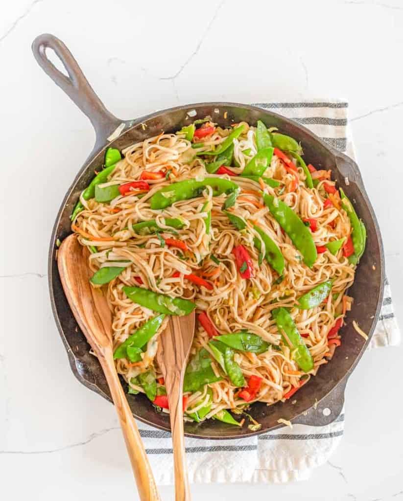 veggie lo mein in bowls served from the cast iron pan