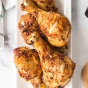 crispy chicken legs stacked on a white plate