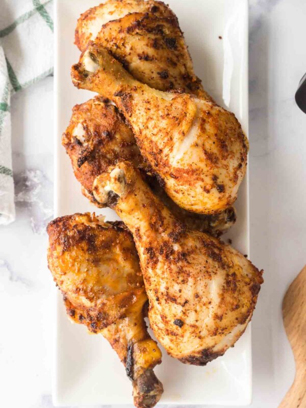 crispy chicken legs stacked on a white plate