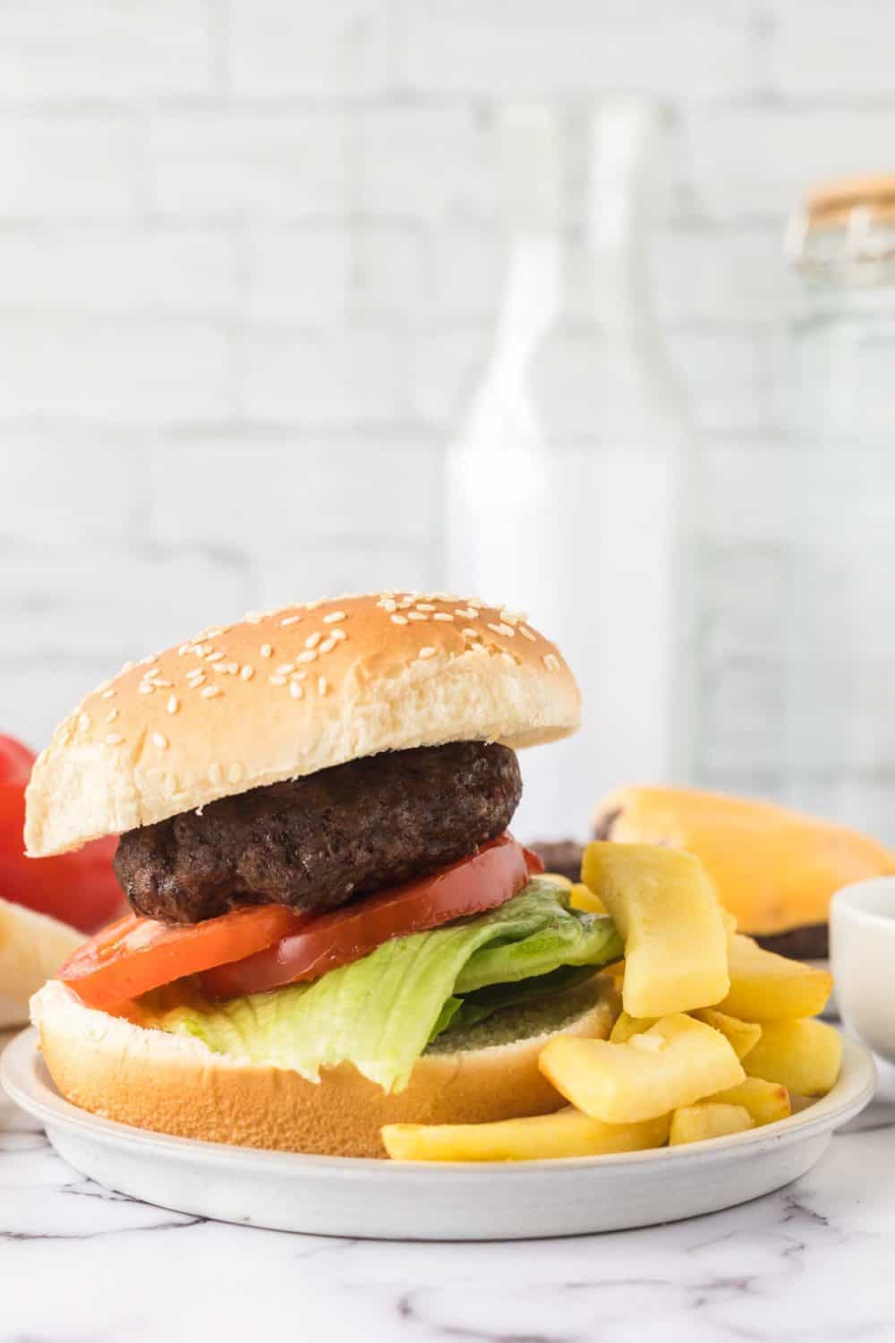 air fryer hamburger and chips on a white plate side view