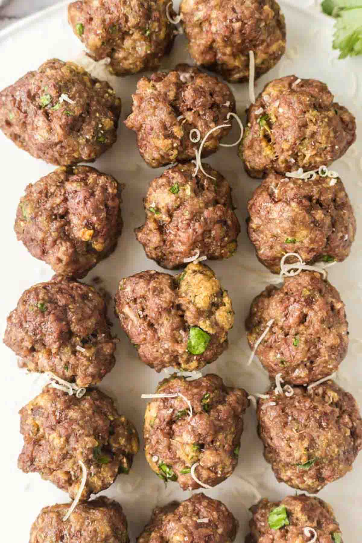 close up top view of baked meatballs in rows on a platter