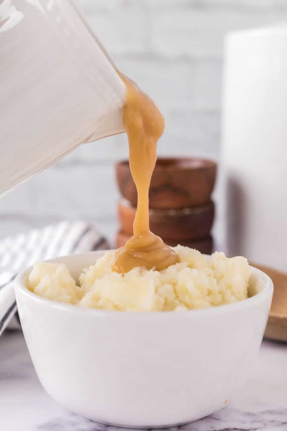 white gravy serving dish with brown gravy poured over mashed potatoes