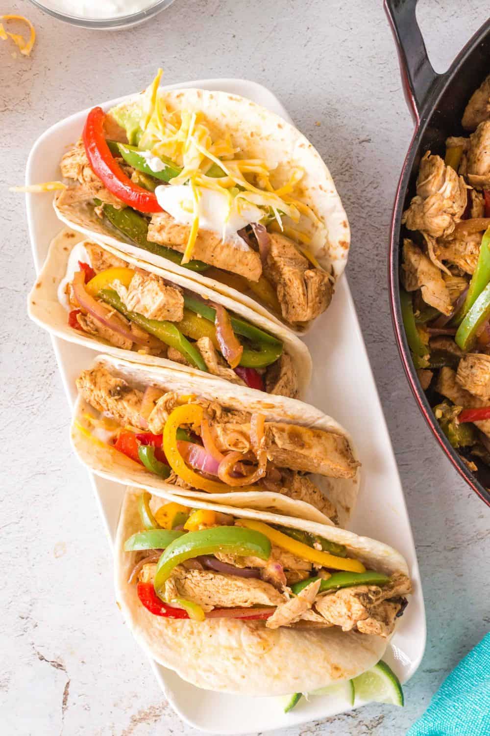 4 chicken fajitas with peppers and onions in a flour tortilla.