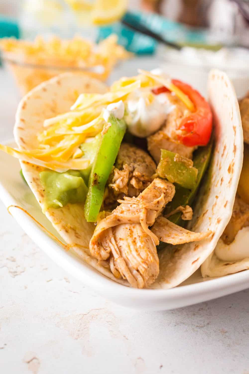 Close up view of chicken fajitas wrapped in a flour tortilla with bell peppers. 