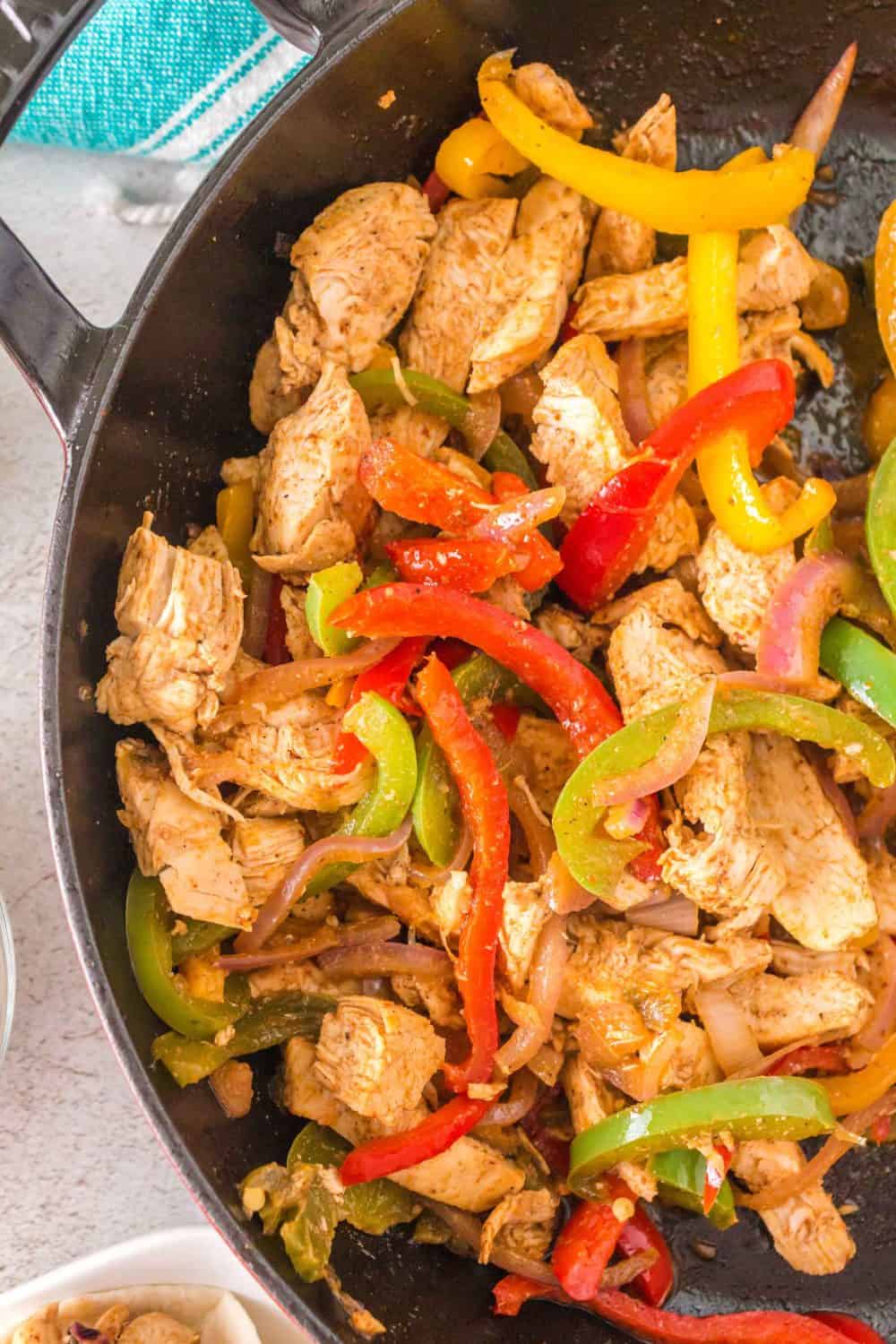cast iron pan with chicken fajita meat and peppers cooked