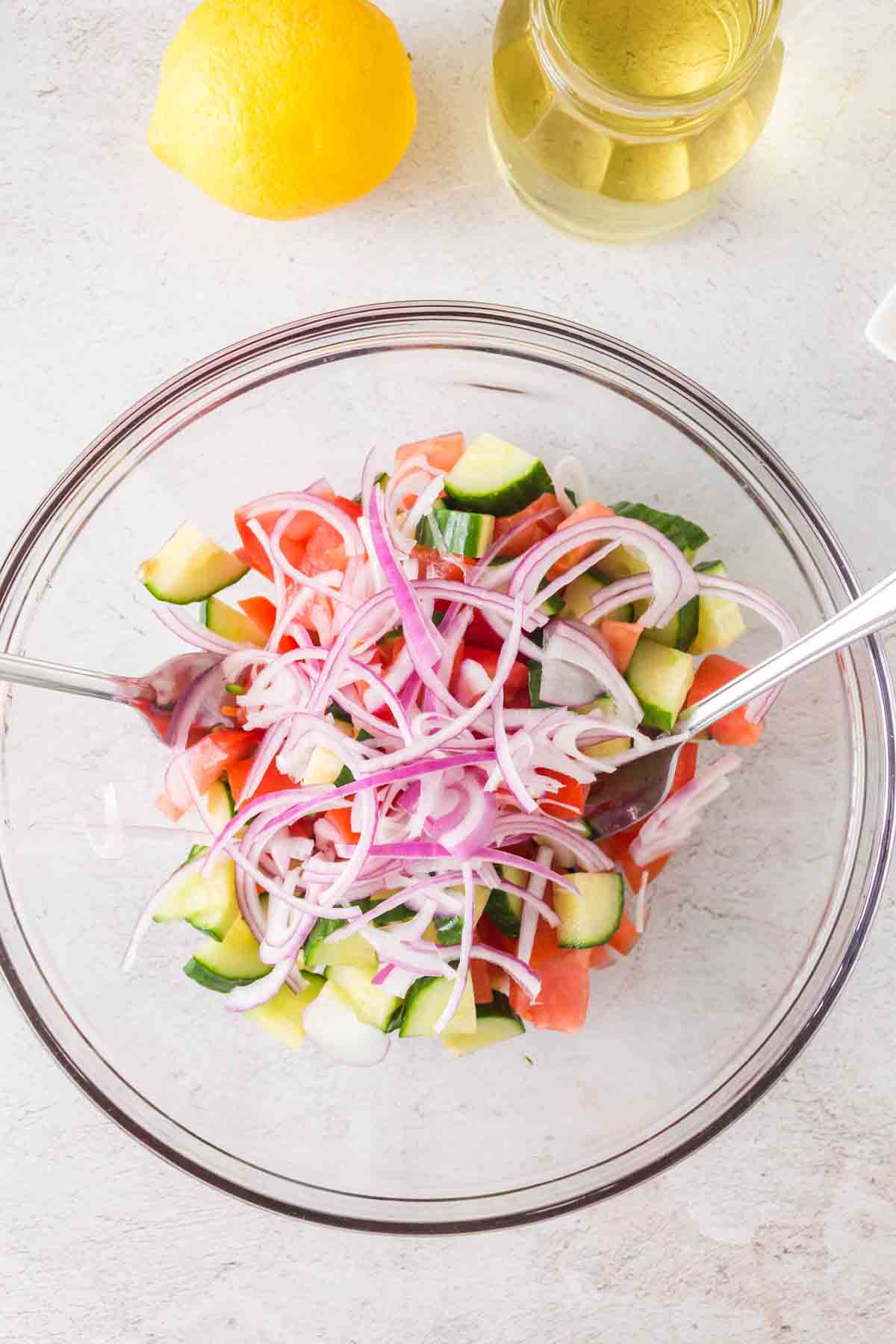 Ingredients for cucumber and tomato salad in a mixing bowl.