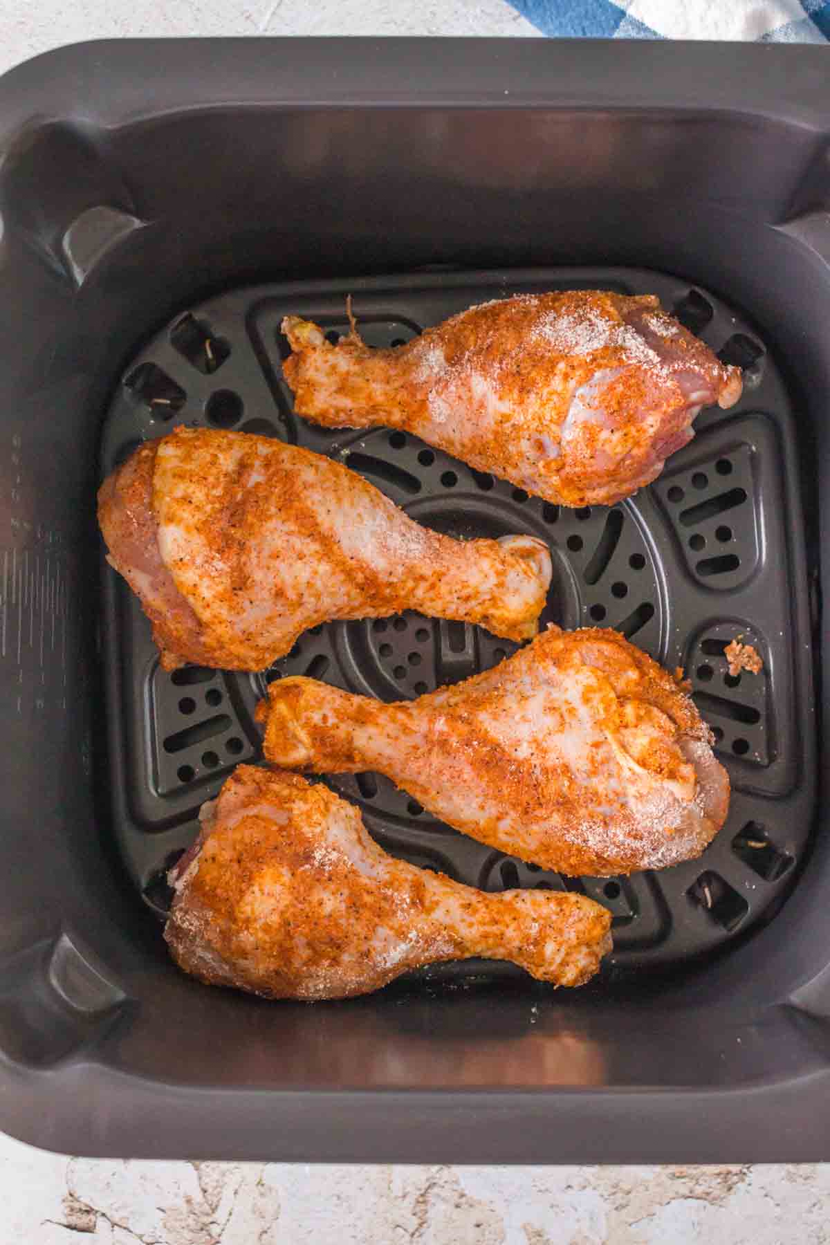 raw and lightly floured and seasoned chicken drumsticks in an air fryer