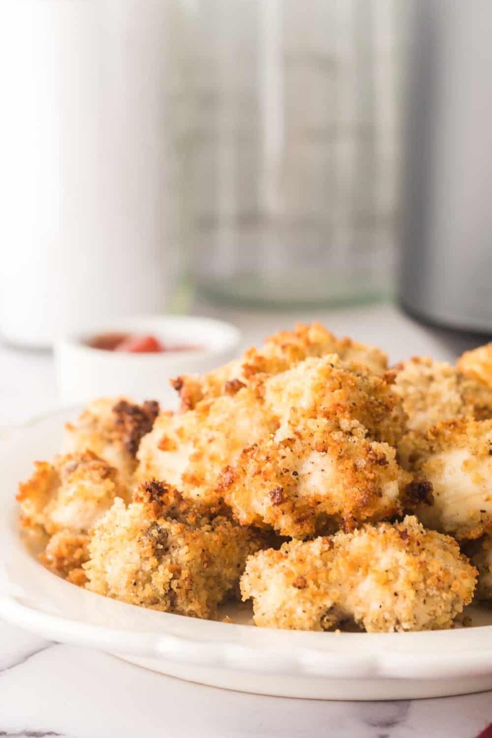 air fryer chicken nuggets on a white plate with ketchup on the side