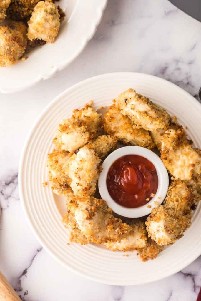 air fryer chicken nuggets on a white plate with ketchup in the middle