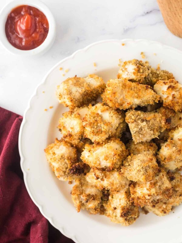 air fryer chicken nuggets on a white plate with ketchup on the side