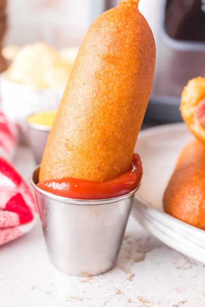 air fried corn dog dipped into a dish of ketchup