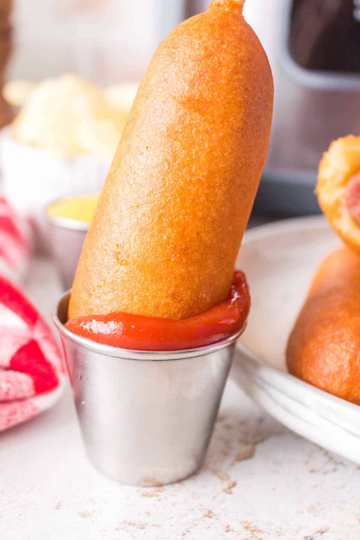 air fried corn dog dipped into a dish of ketchup