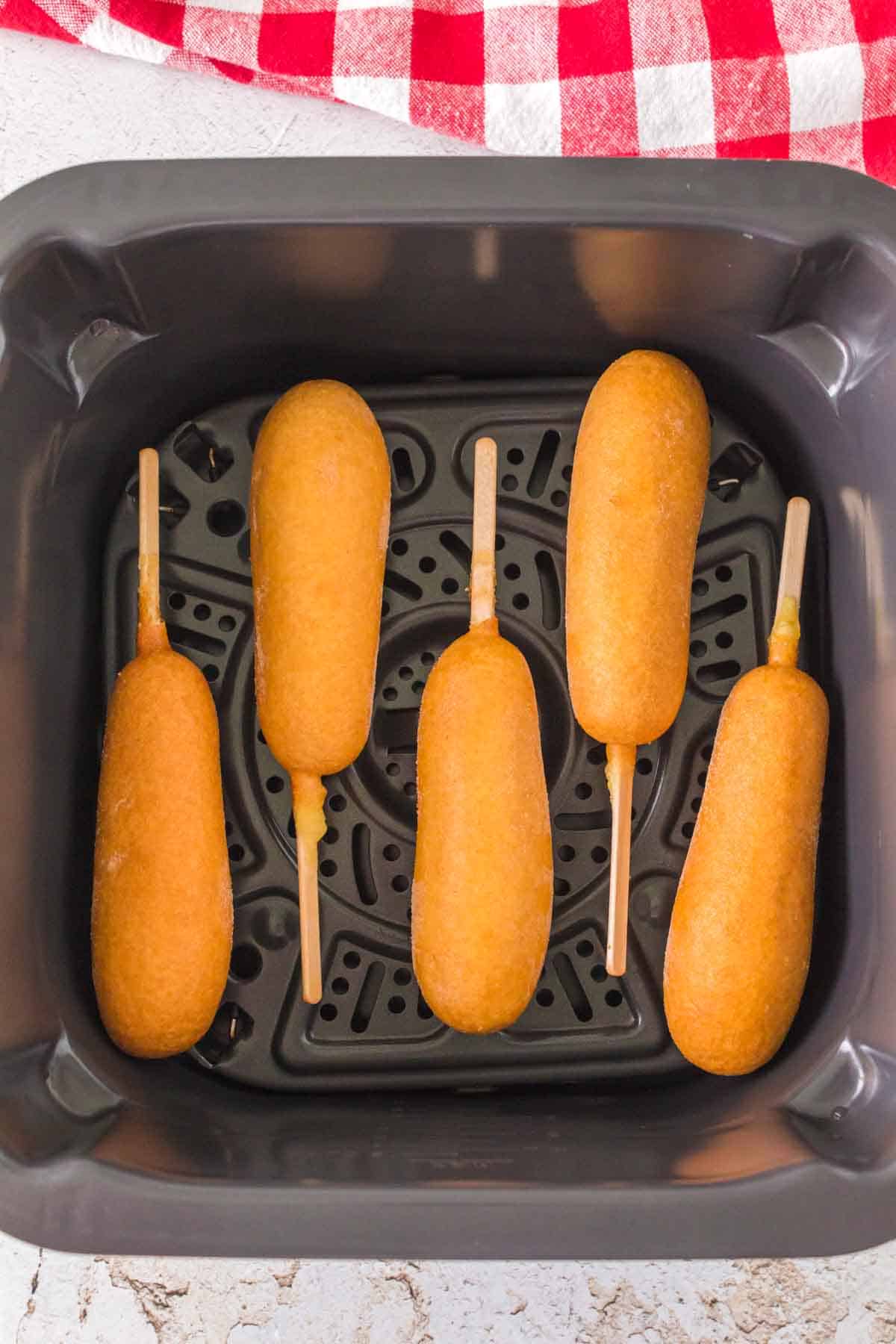 air fryer corn dogs lined up on in the basket