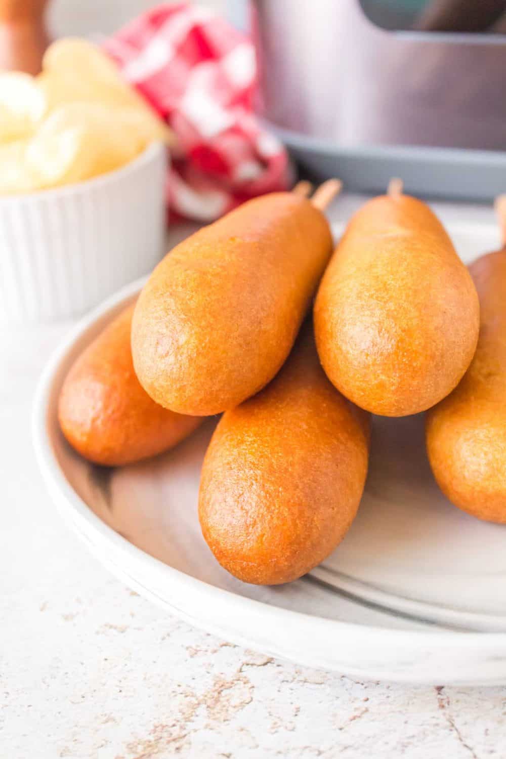 air fryer corn dogs stacked on a plate with ketchup and mustard